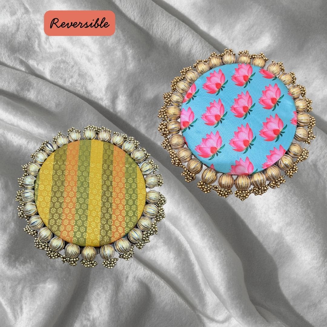 Two round Patola brocade mats on silver satin, one in yellow and green stripes and one pale blue with pink roses.