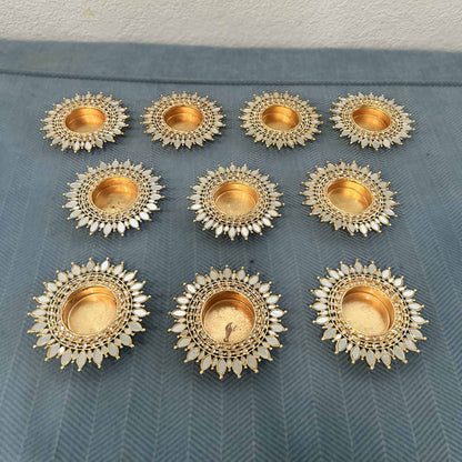 Ten gold mirror sunflower tea light holders in rows on a blue herringbone cloth