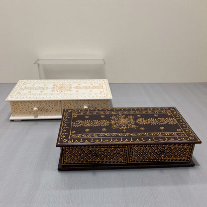 Two ornate wooden boxes on a gray surface with a plain background