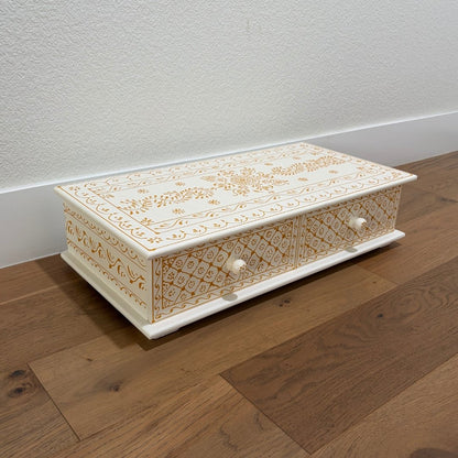 Decorative wooden box with intricate gold patterns on a wooden floor.