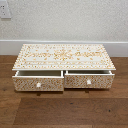 Decorative wooden box with intricate gold patterns on a wooden floor.