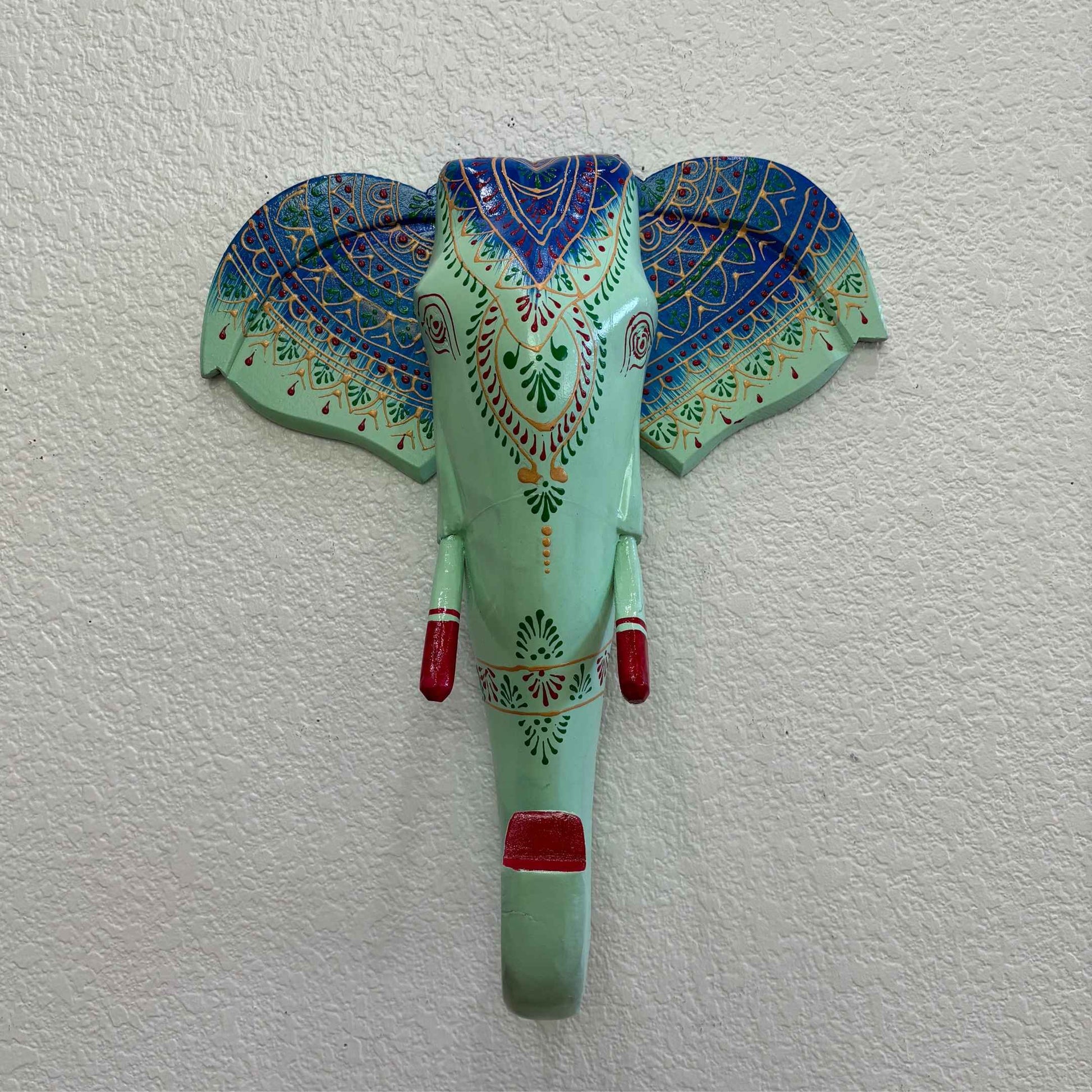 Close-up of the intricate hand-carved details on the wooden mint green elephant head