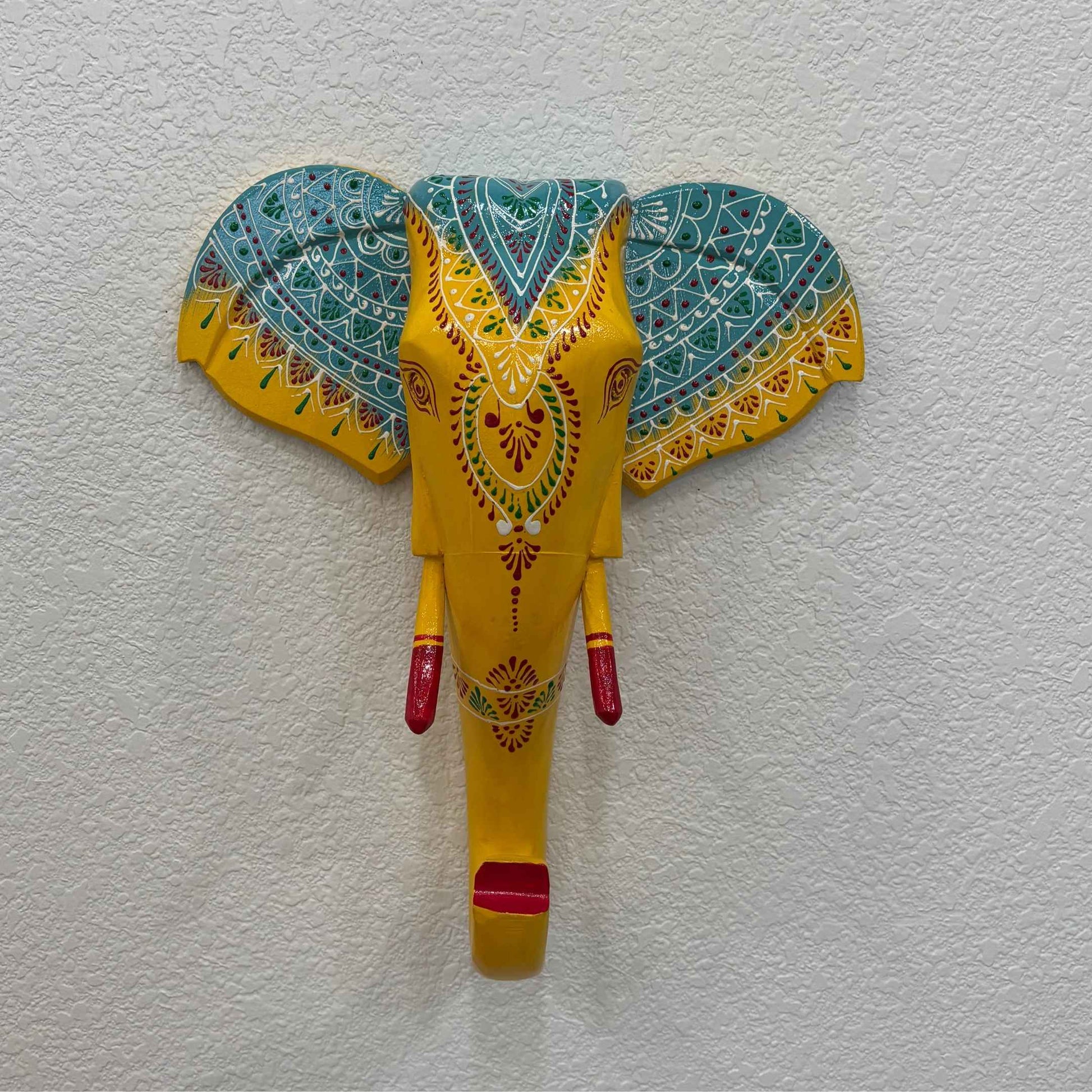 The wooden yellow elephant head displayed on a living room wall as a statement decor piece