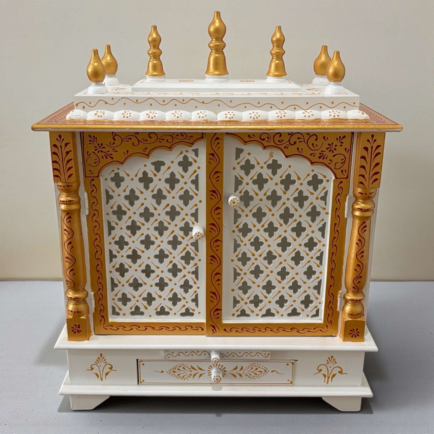 Decorative wooden pooja temple with gold accents and intricate carvings on a plain background