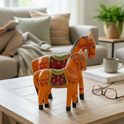 Vibrant orange wooden horse statue pair displayed as a center piece on a modern console table for bohemian home styling.