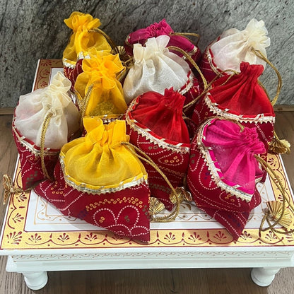 Decorative bags in red, yellow, and white on a decorative tray with a stone wall background.