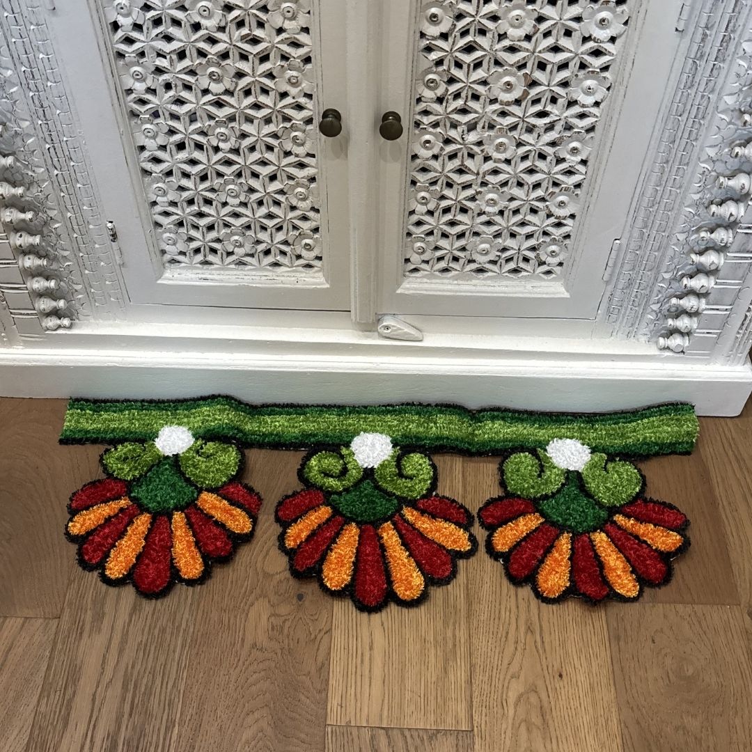 Orange Sunflower rangoli mat on wood floor in front of ornate white cabinet Indian decor