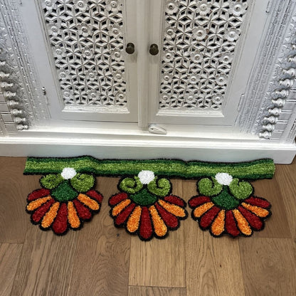 Orange Sunflower rangoli mat on wood floor in front of ornate white cabinet Indian decor