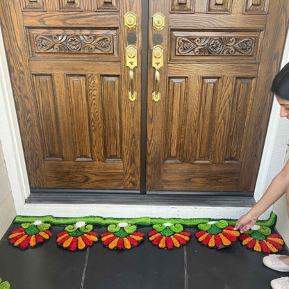 Handmade orange sunflower rangoli mat placed at double front door Indian festive entry decor