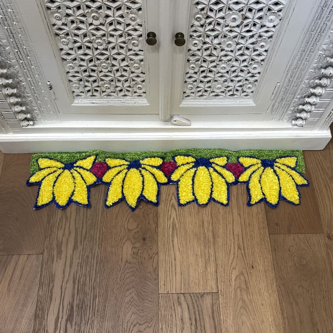 Yellow Lotus rangoli mat on wood floor in front of ornate white cabinet Indian decor