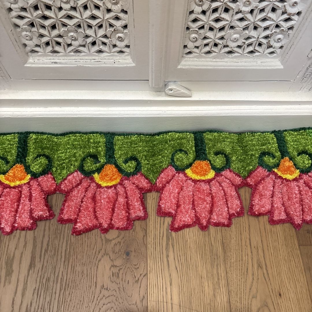 Pink Lotus rangoli mat on wood floor in front of ornate white cabinet Indian decor