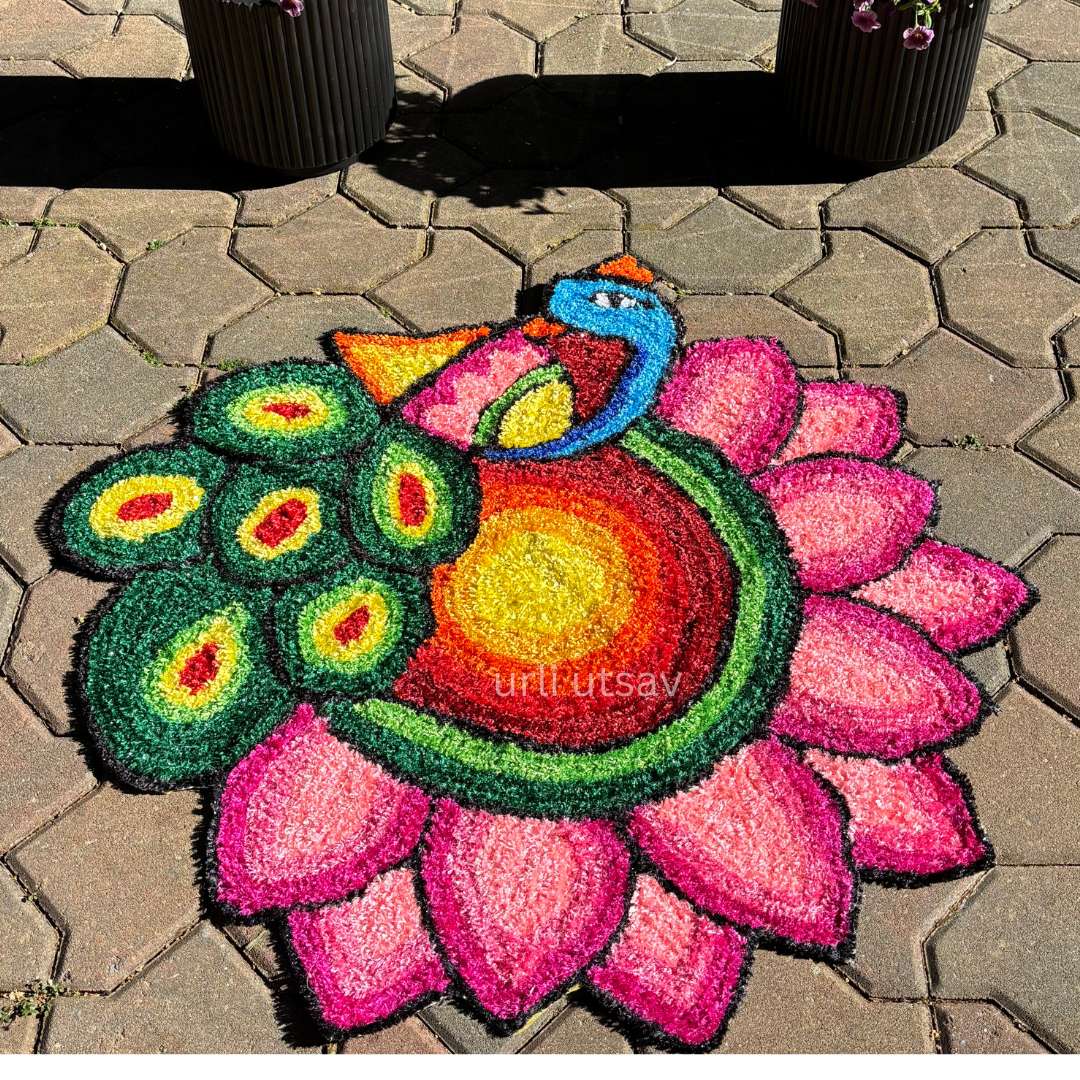 Vibrant peacock-themed rangoli mat with green outer petals and a stylized bird motif at the center, displayed on stone flooring