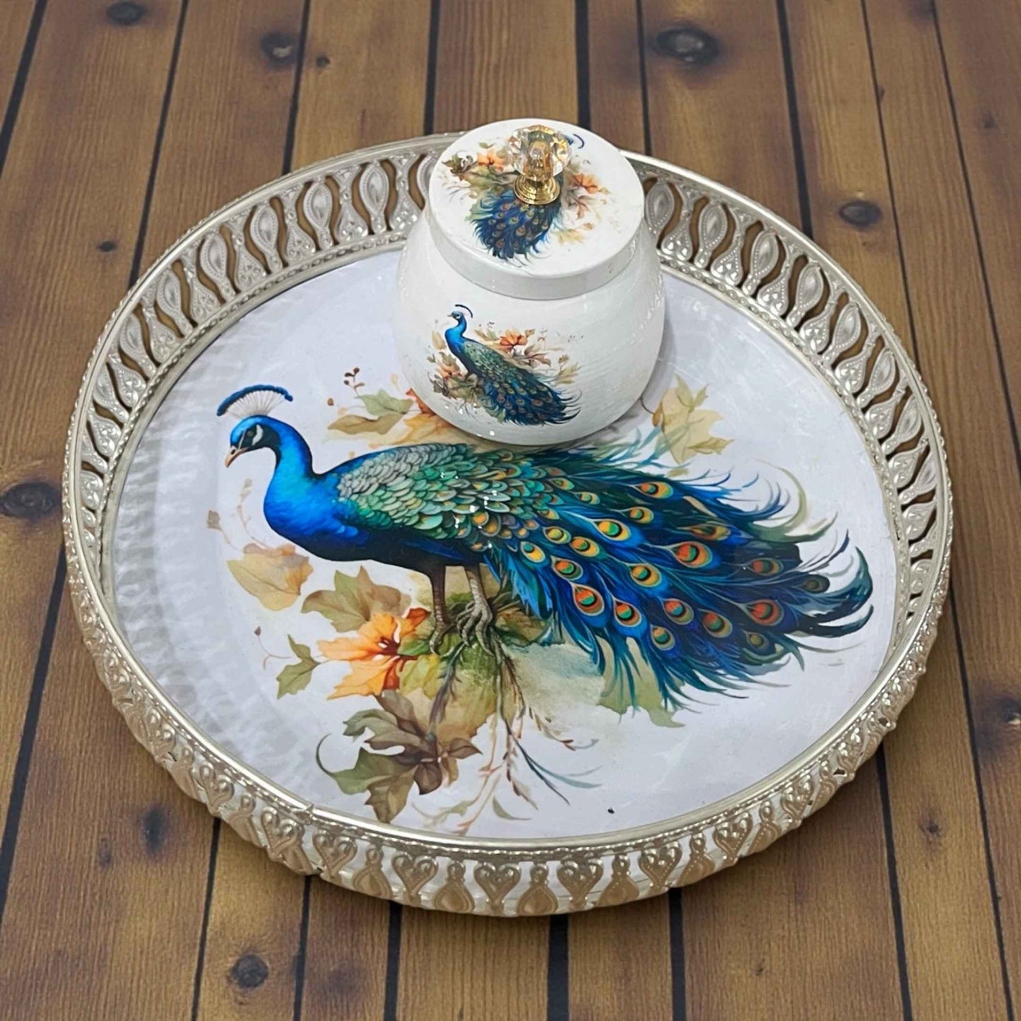 Decorative teapot and tray with peacock design on a wooden surface