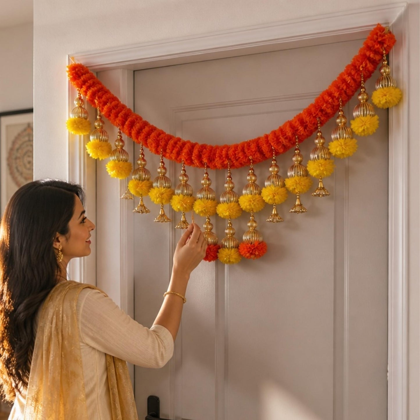 Kesar orange marigold toran with yellow pompoms and gold jhumka bells on door