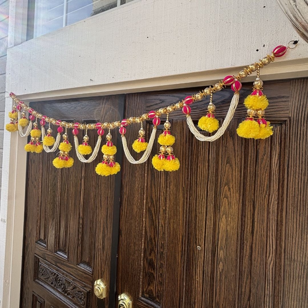 Decorative garland with yellow and red pom-poms hanging above a wooden door.