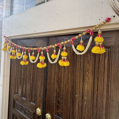 Decorative garland with yellow and red pom-poms hanging above a wooden door.