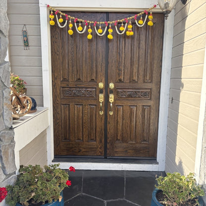 Decorative garland above a wooden door with plants on either side.