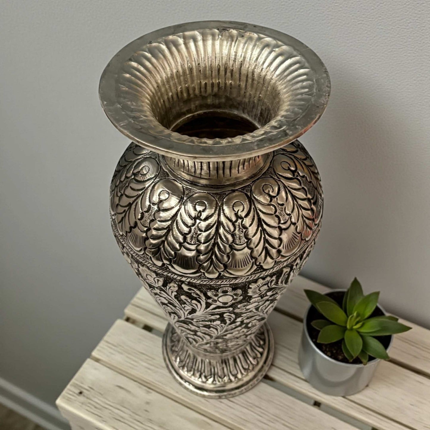 A close-up view of the handcrafted foliage etchings on a German silver plated copper vase.