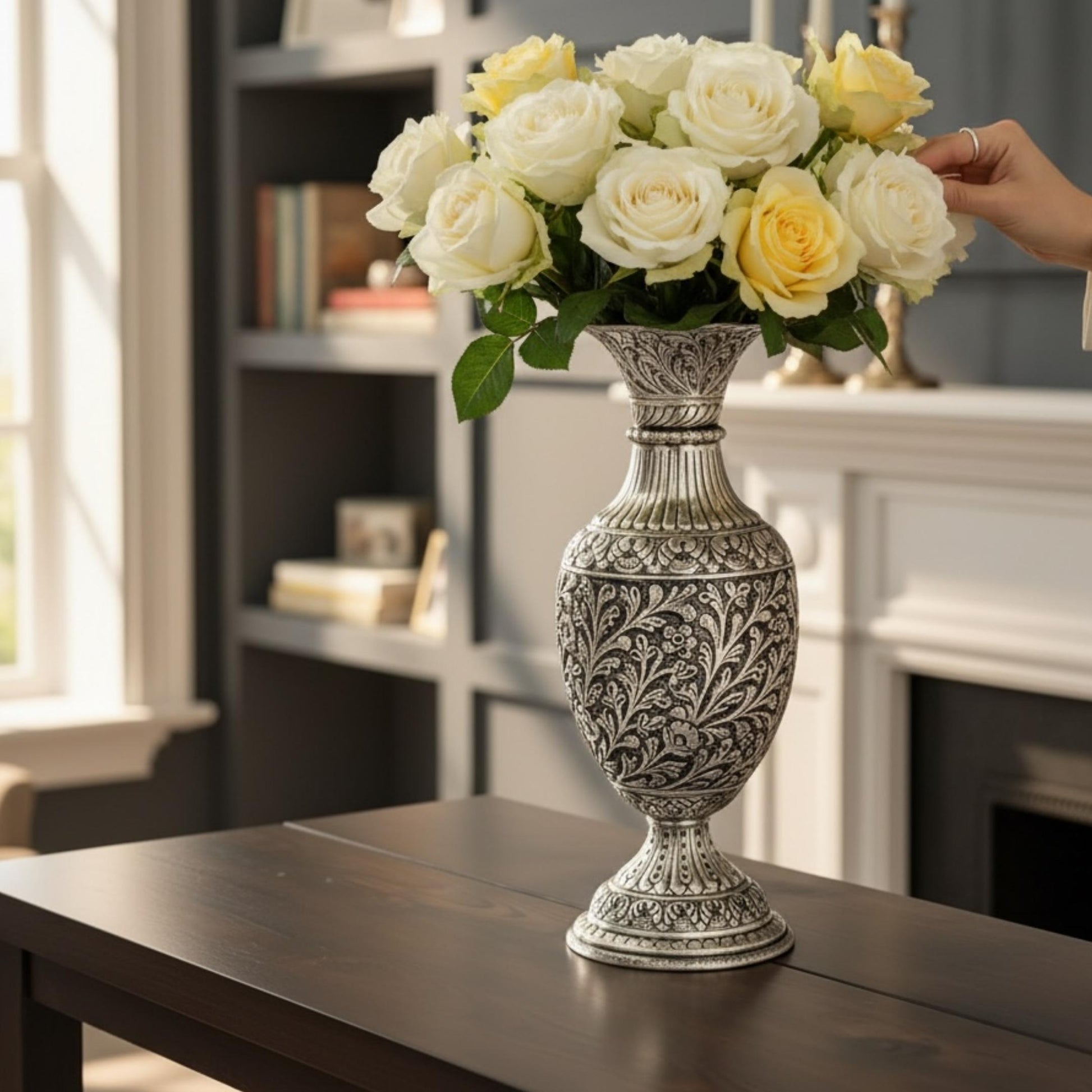 A refined antique silver vase filled with white roses on a dark table, highlighting traditional craftsmanship.