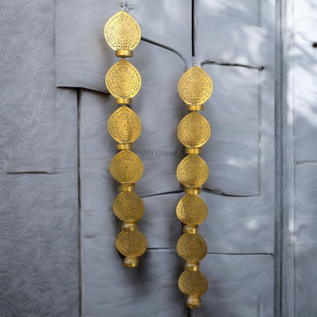 Gold earrings with intricate designs hanging against a textured gray background