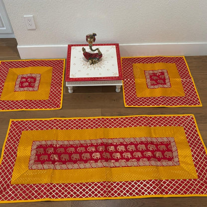 Red and yellow elephant motif silk brocade runner and mats displayed flat—vibrant pooja aasan set for Diwali and meditation.