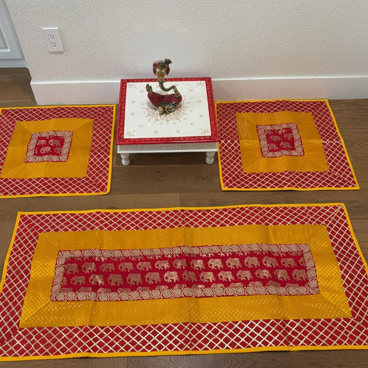 Red and yellow elephant motif silk brocade runner and mats displayed flat—vibrant pooja aasan set for Diwali and meditation.