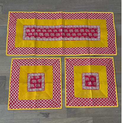Handcrafted red-yellow elephant motif runner in silk brocade, large and small aasan mats layered for festive Ganesh setup.