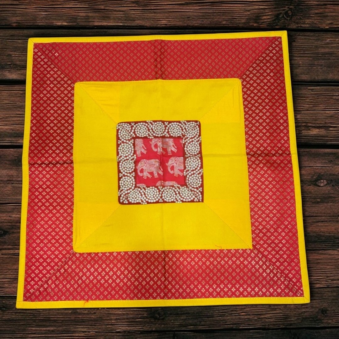 Red and yellow fabric with a central square featuring elephant patterns on a wooden surface
