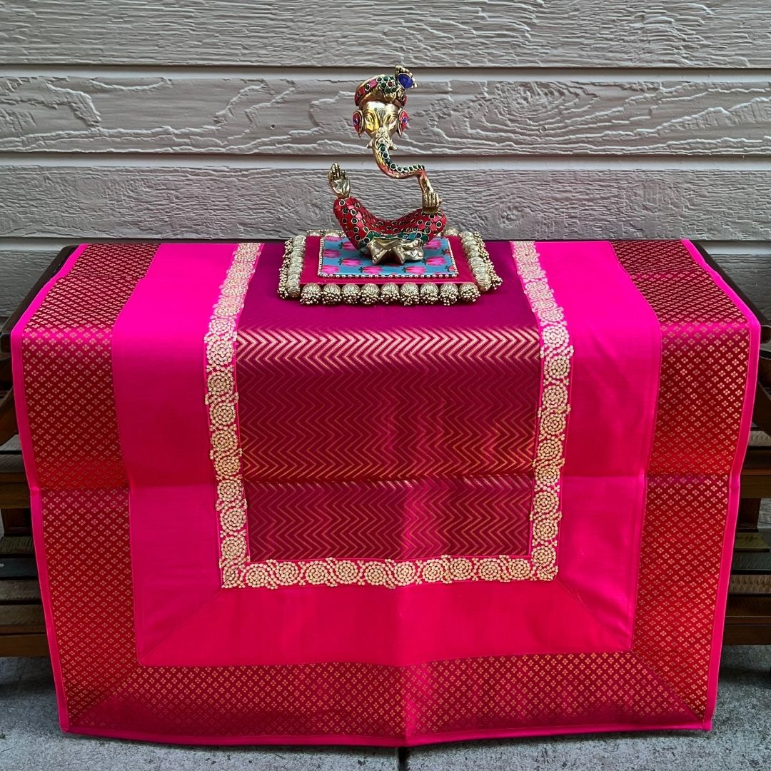 Styled Diwali altar: Pink Zigzag Banarasi brocade pooja aasan with diya and marigold — prayer mat décor