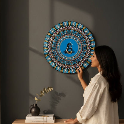 Woman installing a decorative 2ft adiyogi wall art against a dark wall