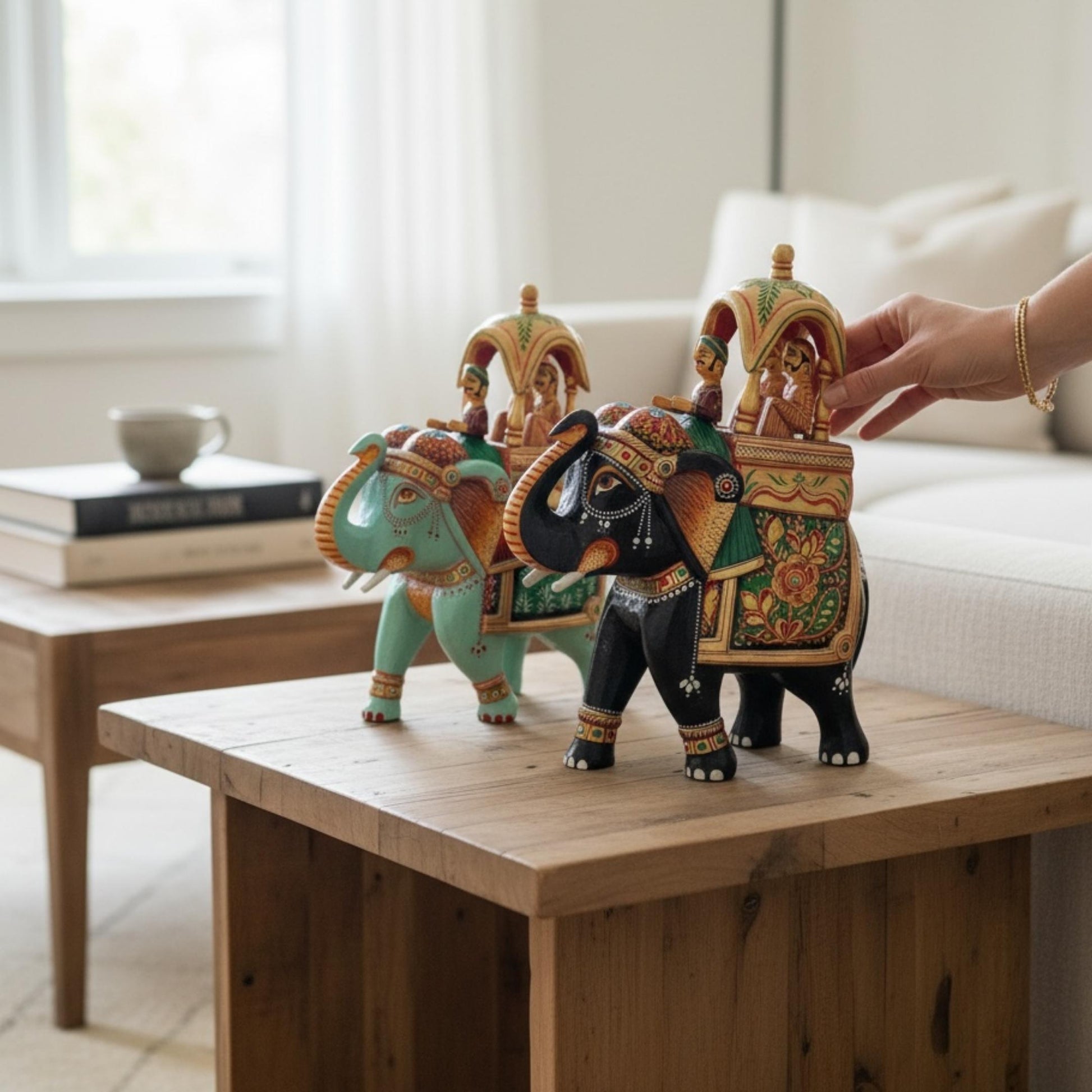 Living room décor shot of the Walking Ambabari Elephant wood statue placed on wooden surface with furniture, styled as centerpiece accent.
