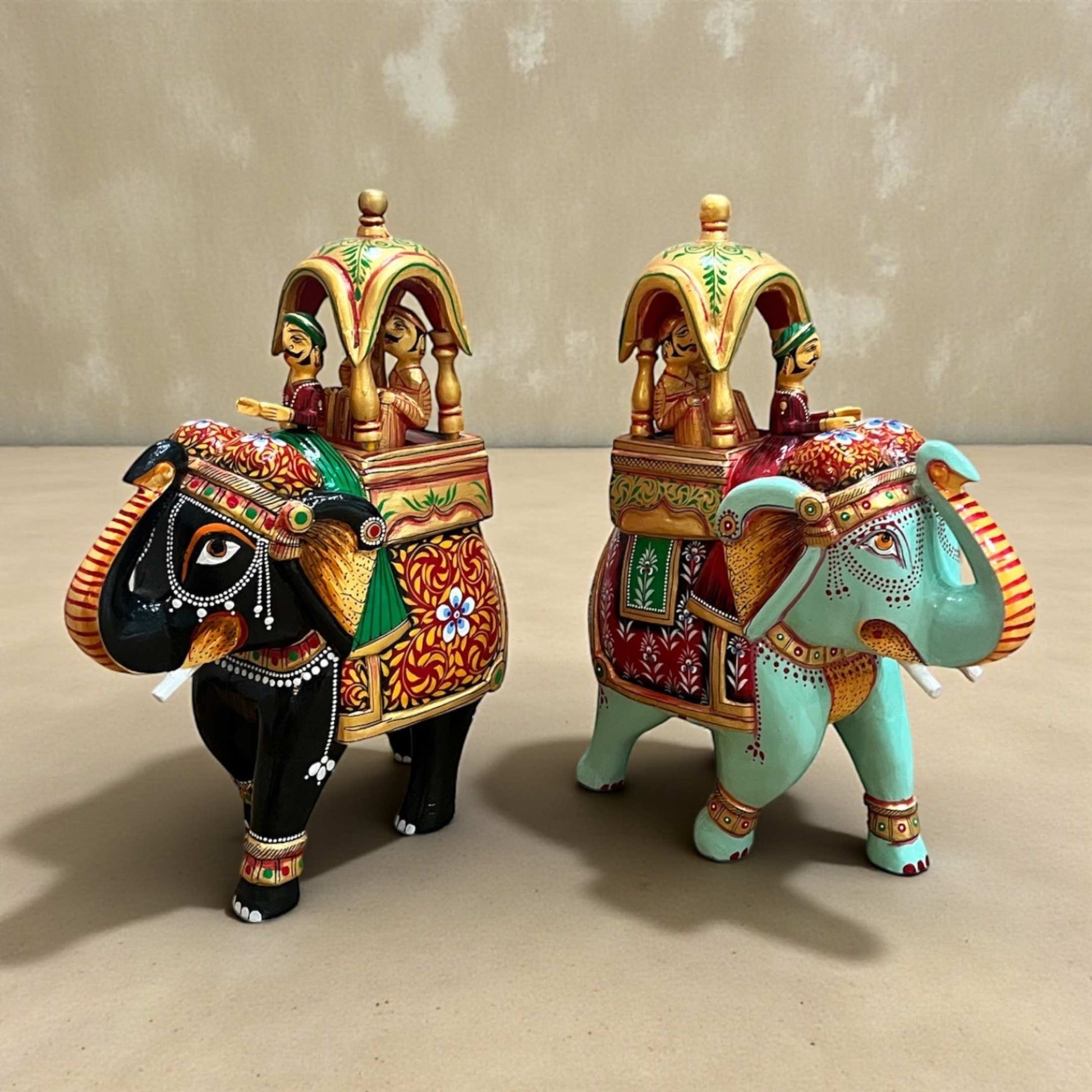 Pair of Walking Ambabari Elephant handpainted wooden decor statues with carved riders, vibrant accents on beige background.