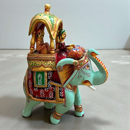 Decorative Walking Ambabari Elephant statue featuring carved riders atop the elephant and painted accents on plain backdrop.