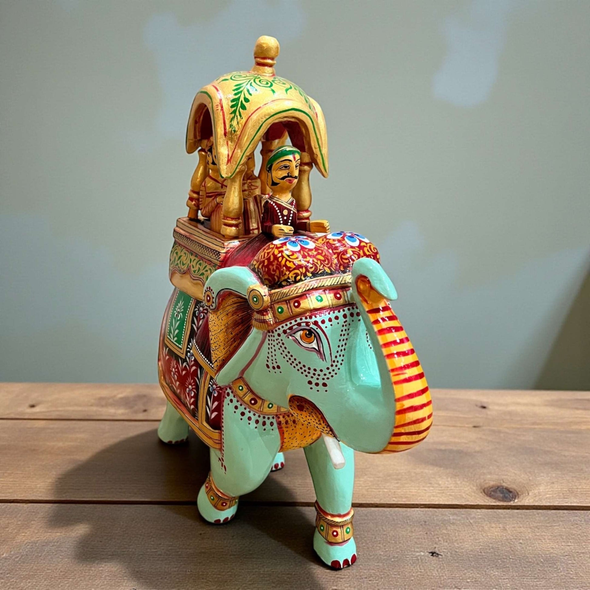 Close-up of Walking Ambabari Elephant handcrafted sculpture on wooden surface highlighting carved headdress, decorative motifs, and rich matte finish.