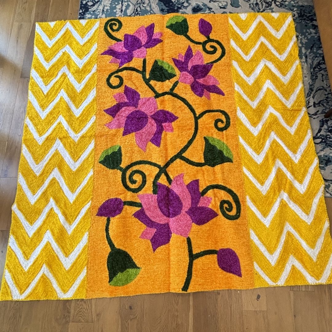 Orange and gold lotus backdrop with purple and pink flowers and yellow-white chevron panels laid flat near a rug