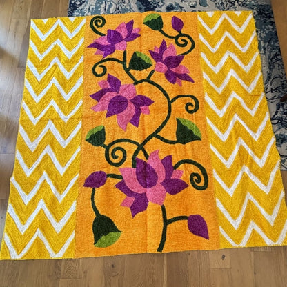 Orange and gold lotus backdrop with purple and pink flowers and yellow-white chevron panels laid flat near a rug