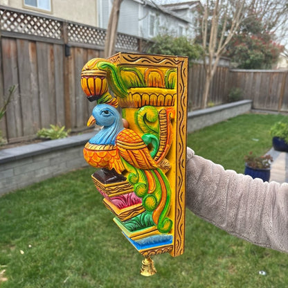 Artisan holding a vibrant hand-painted Indian bird corbel, highlighting the craftsmanship