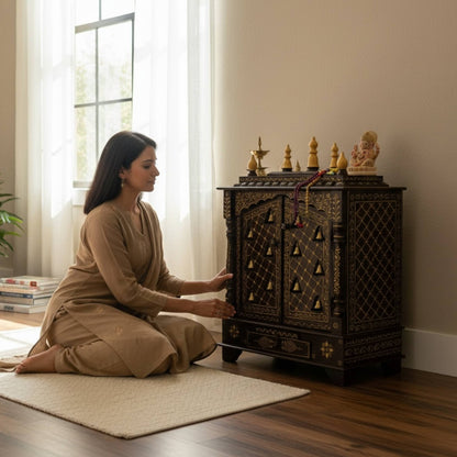 Woman performing puja in front of walnut brown wooden pooja mandir with brass bells