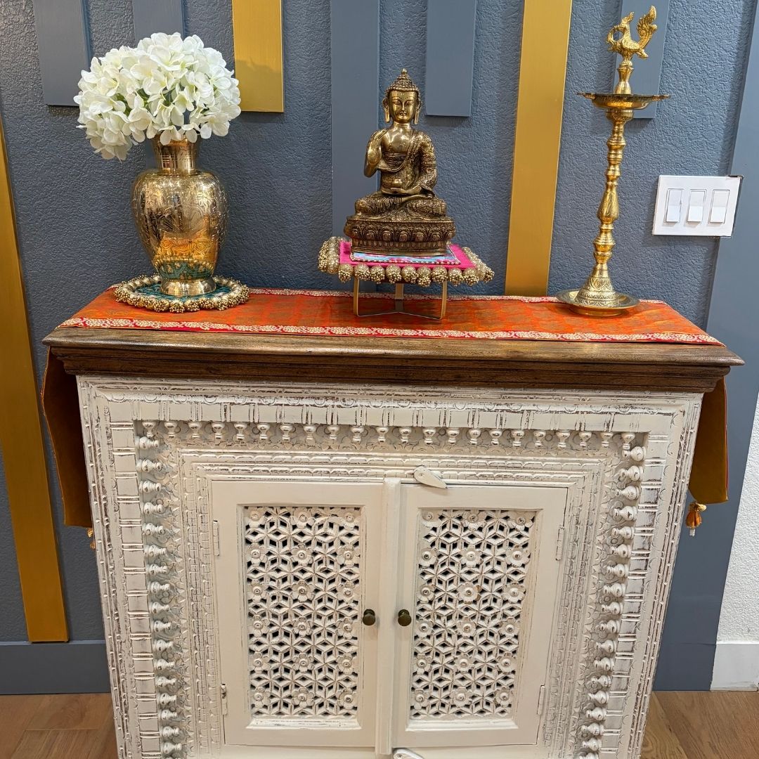 Styled decor scene: Brass Buddha statue with lamp and floral arrangement on cabinet