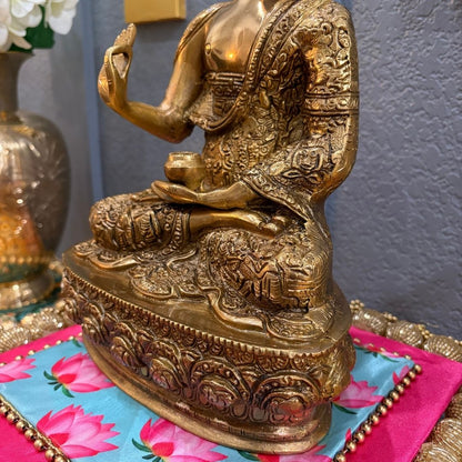 Gold-colored seated Buddha statue on vibrant fabric — spiritual home decor display