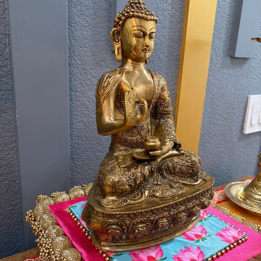 12" Brass Buddha Vitarka Mudra on colorful fabric with blue wall — yoga studio accent