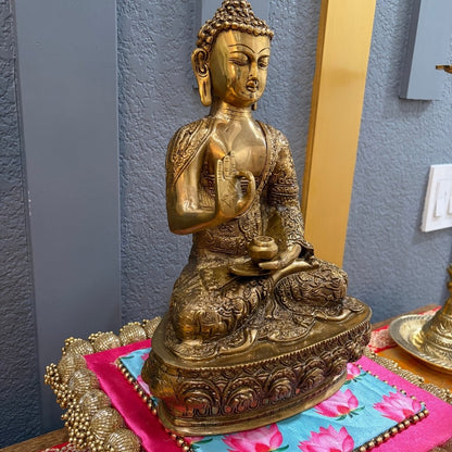 12" Brass Buddha Vitarka Mudra on colorful fabric with blue wall — yoga studio accent