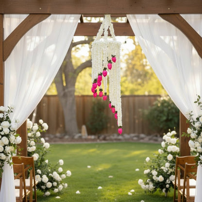 White jasmine chandelier with pink lotus buds hanging under a wedding ceremony arch