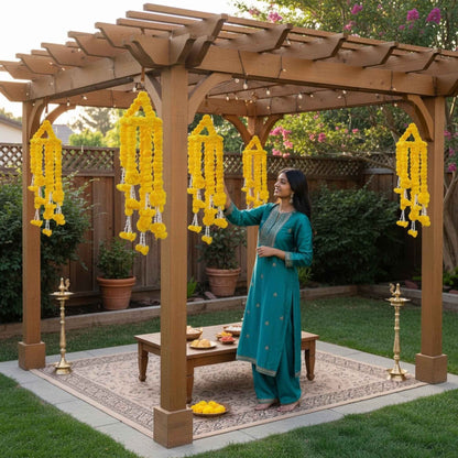 Woman adjusting yellow marigold ball chandelier garlands under wooden pergola with brass diya stands