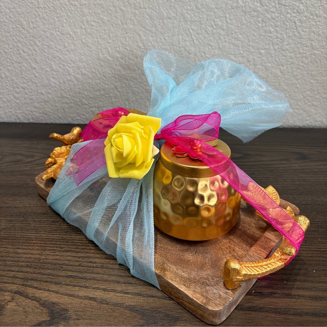 Copper jar, yellow rose, and colorful ribbons tucked on wooden tray — packaging detail of gifting set