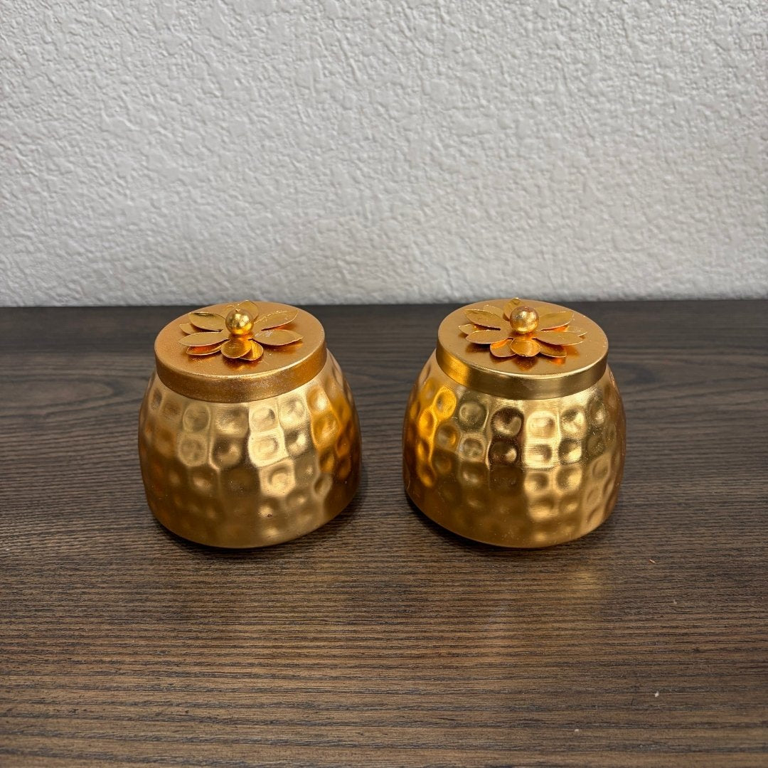 Pair of textured gold‑tone copper storage jars on wooden surface — part of gifting options