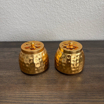 Pair of textured gold‑tone copper storage jars on wooden surface — part of gifting options