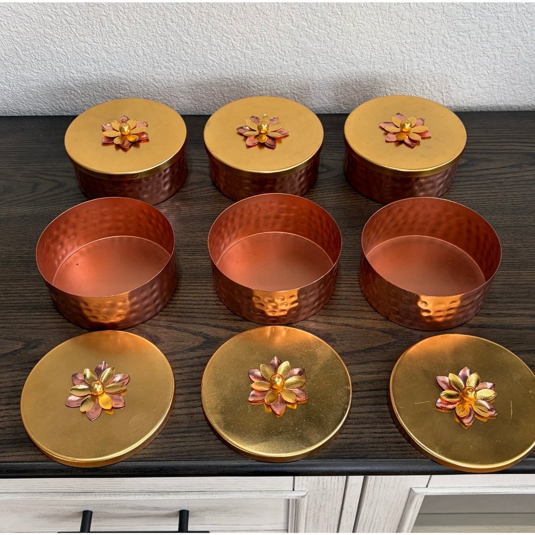 Set of metallic containers with floral-lid design on wood surface — part of six‑box copper set