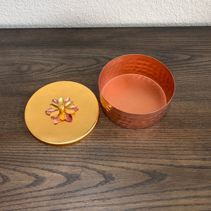 Copper container with a decorative lid on a wooden surface