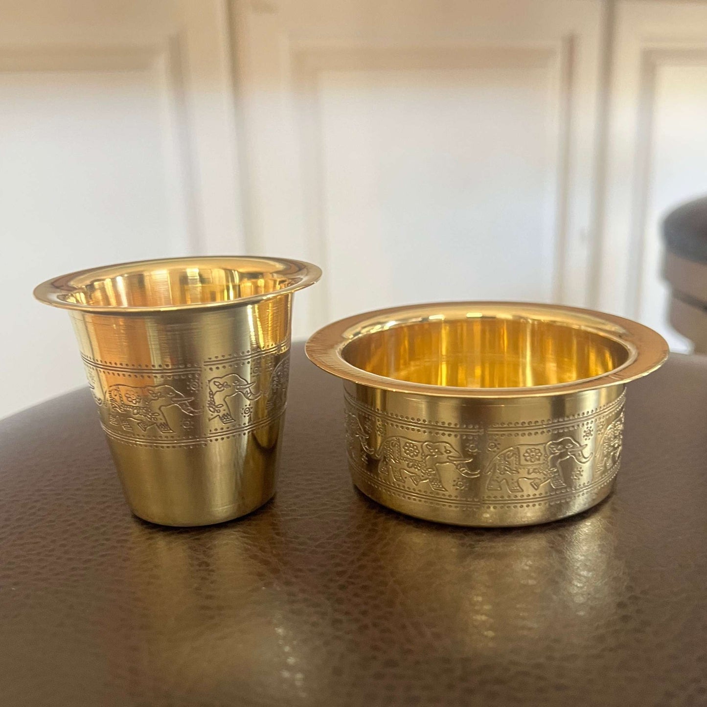 Close-up of brass davara tumbler and collector bowl with engraved elephant motif bands